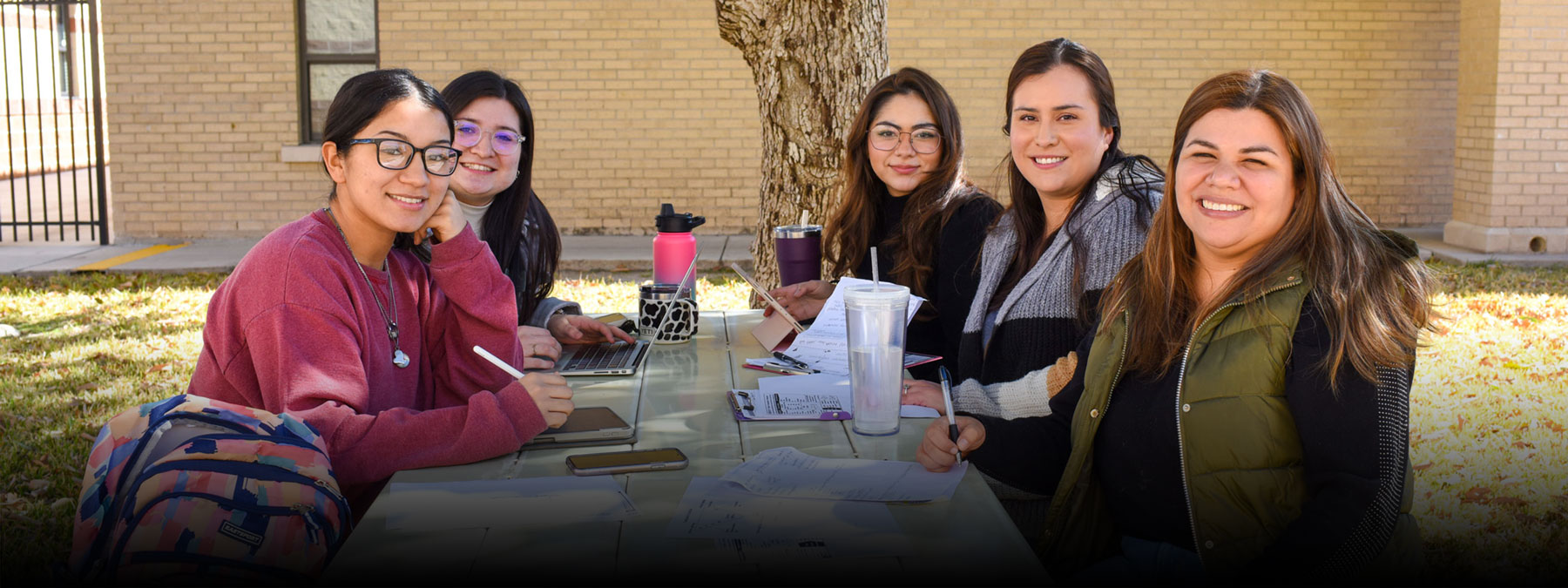Students sit at a picnic table in a courtyard of the Del Rio campus.