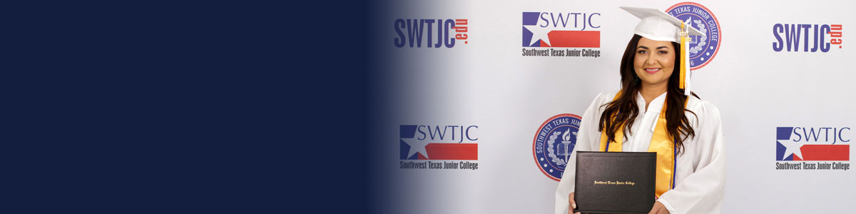 Nursing student in graduation regalia posed in front of an SWTJC logo banner while holding their degree.